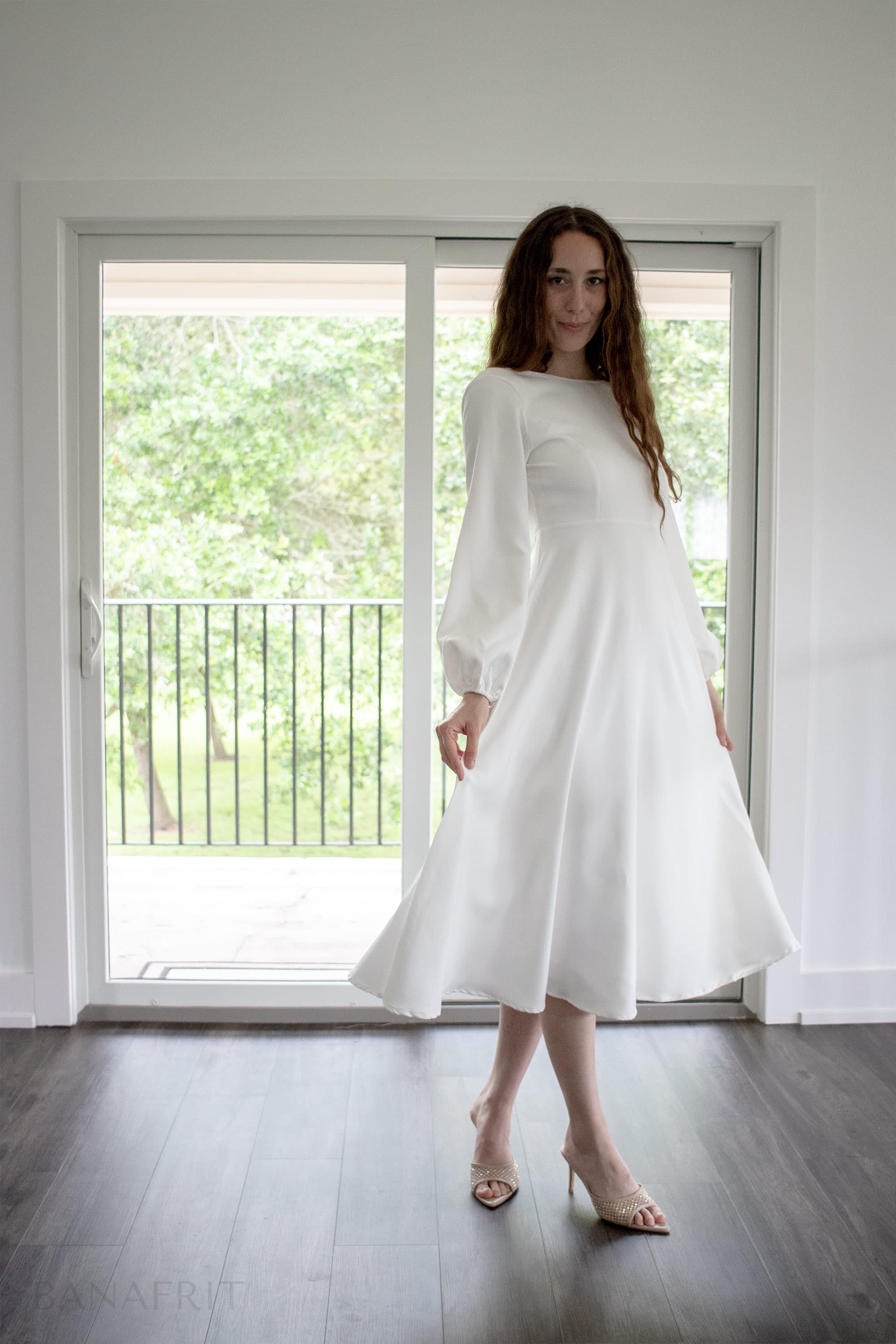 Fine art portrait — woman in white dress, poised in natural daylight, minimalist interior